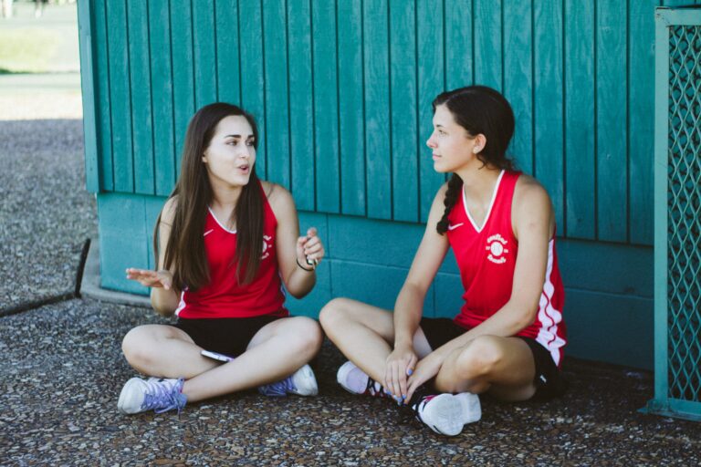 2 jeunes sportives assises par terre en train de discuter